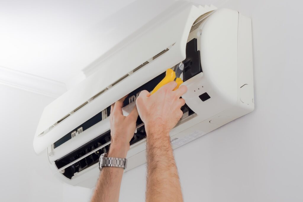 Hands working on air conditioner maintenance project