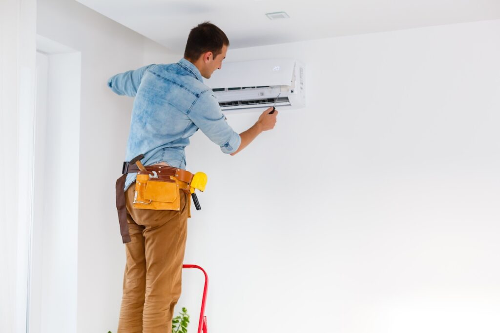 Worker completing maintenance on the air conditioner in the new apartment
