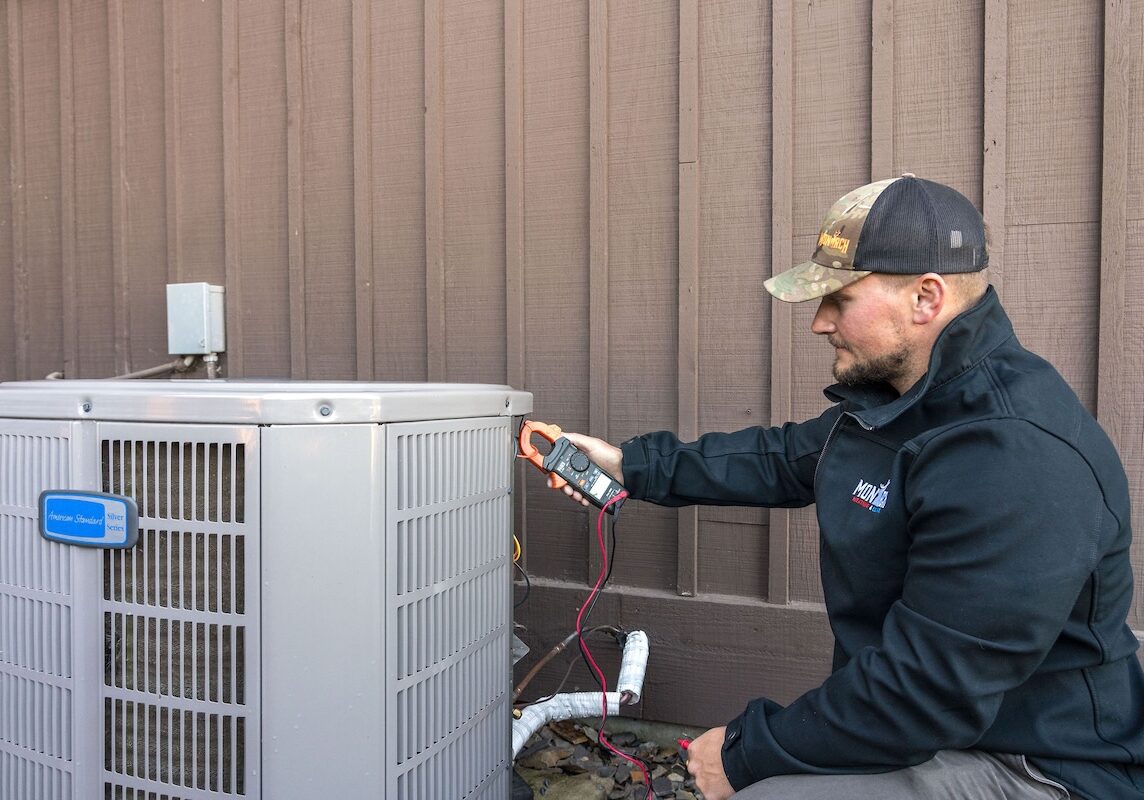 testing heat pump Monarch employee working on heat pump outside of house