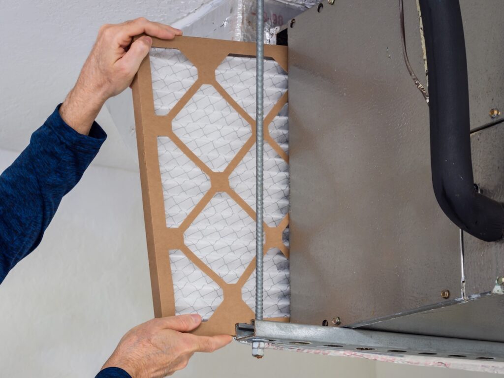 HVAC service technician changing dirty indoor air filter in residential heating and air conditioning system. Home air duct ventilation system maintenance for clean air. HVAC filter brown and white