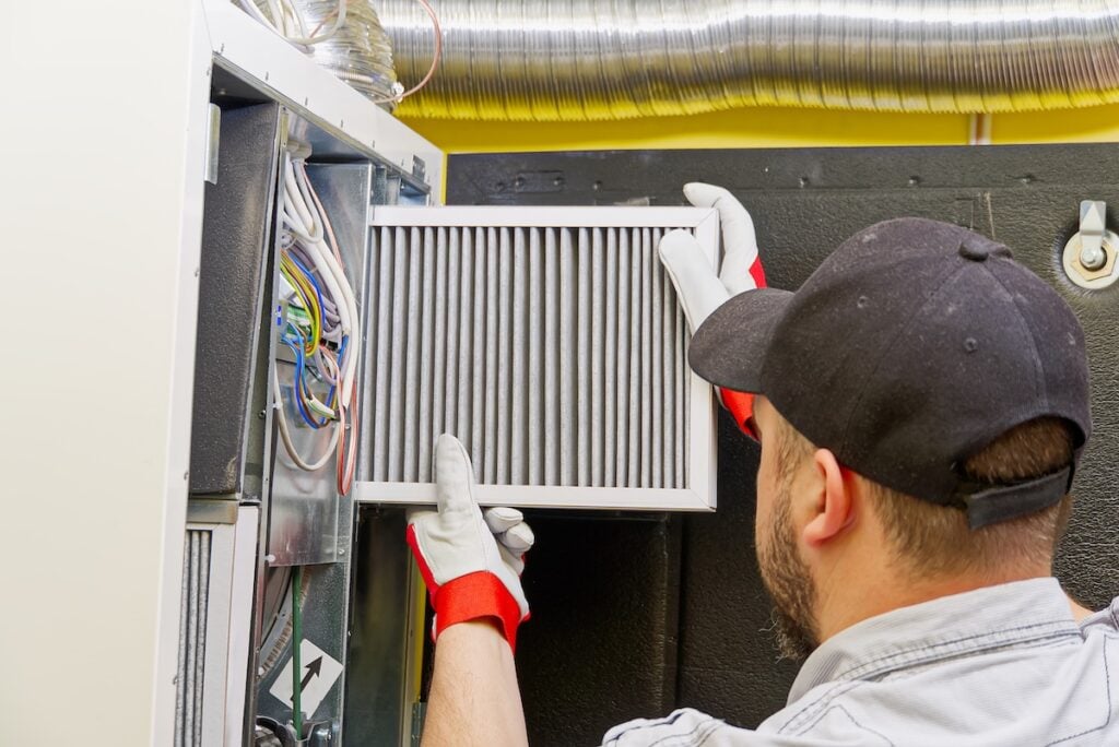 HVAC technician changing filter for furnace