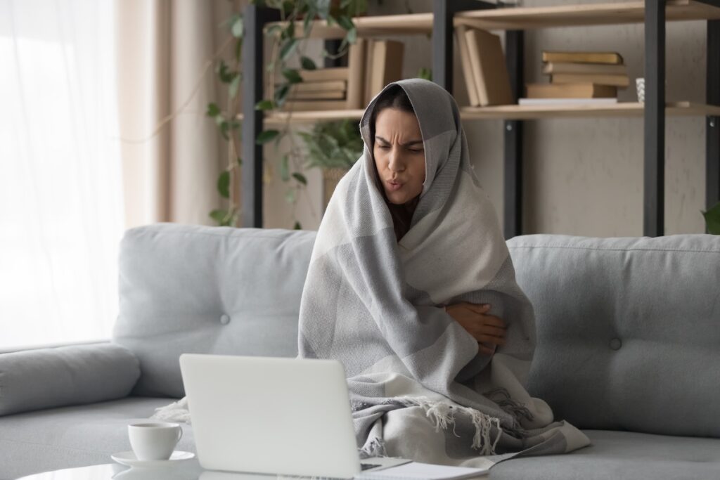 Sick woman feel cold at home covered with blanket Heat not working in house causes woman to be cold and wrapped in blankets
