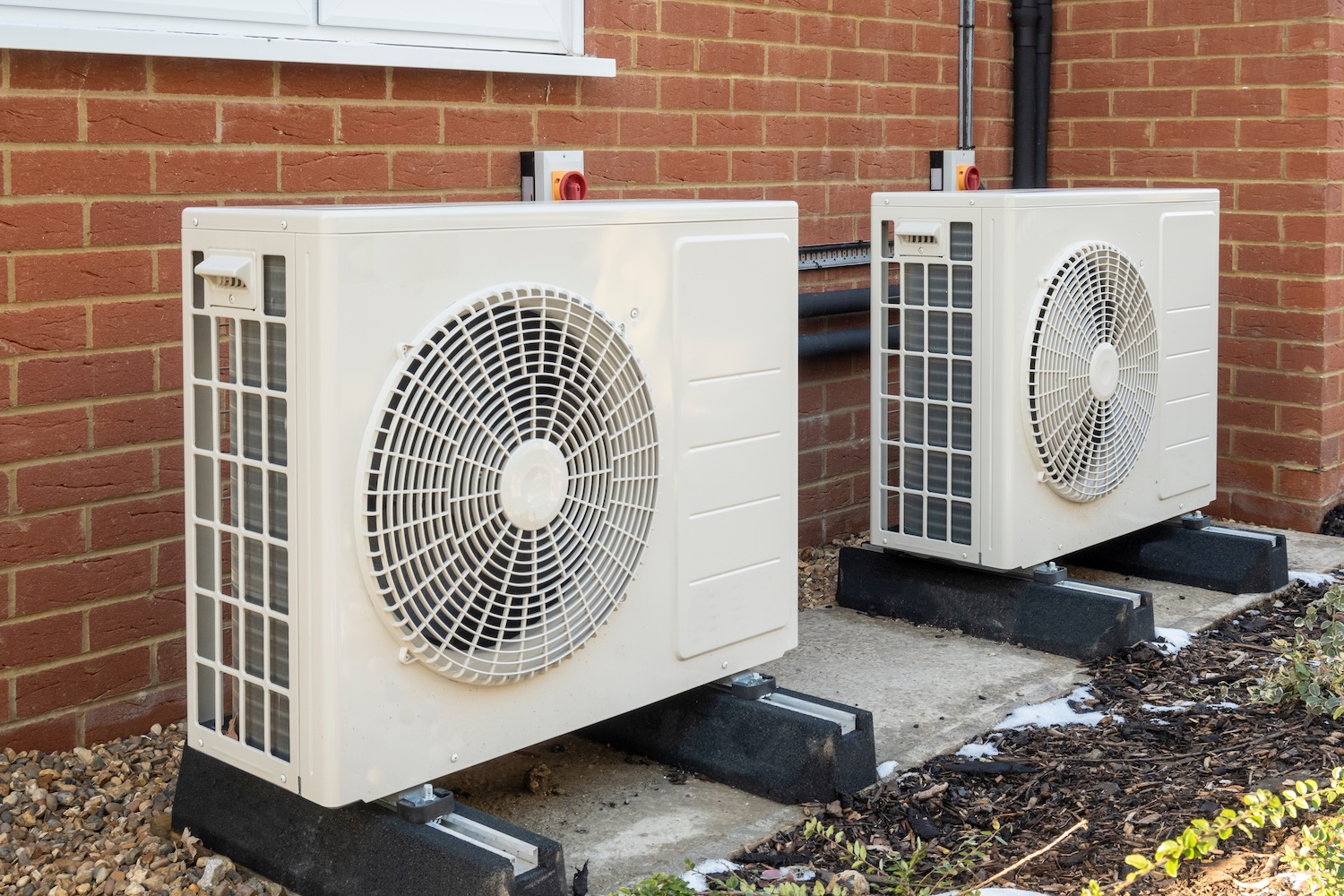 Heat pumps installed on the outside of a modern house Two air source heat pumps installed on the exterior of a modern house