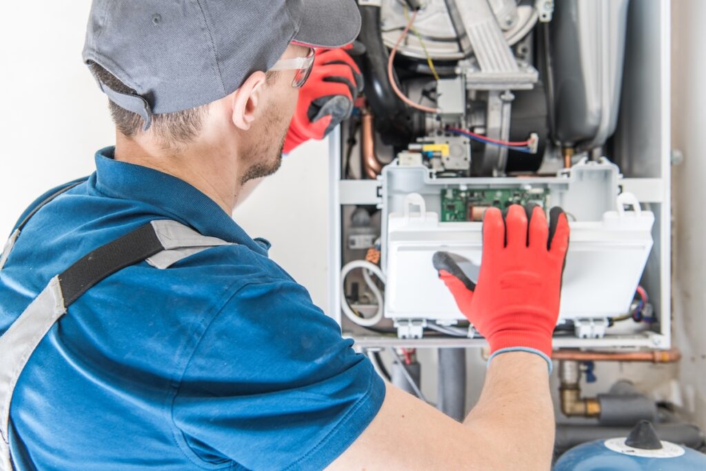Heating Central Gas Furnace Technician installing heating system with the Residential Heating Equipment.