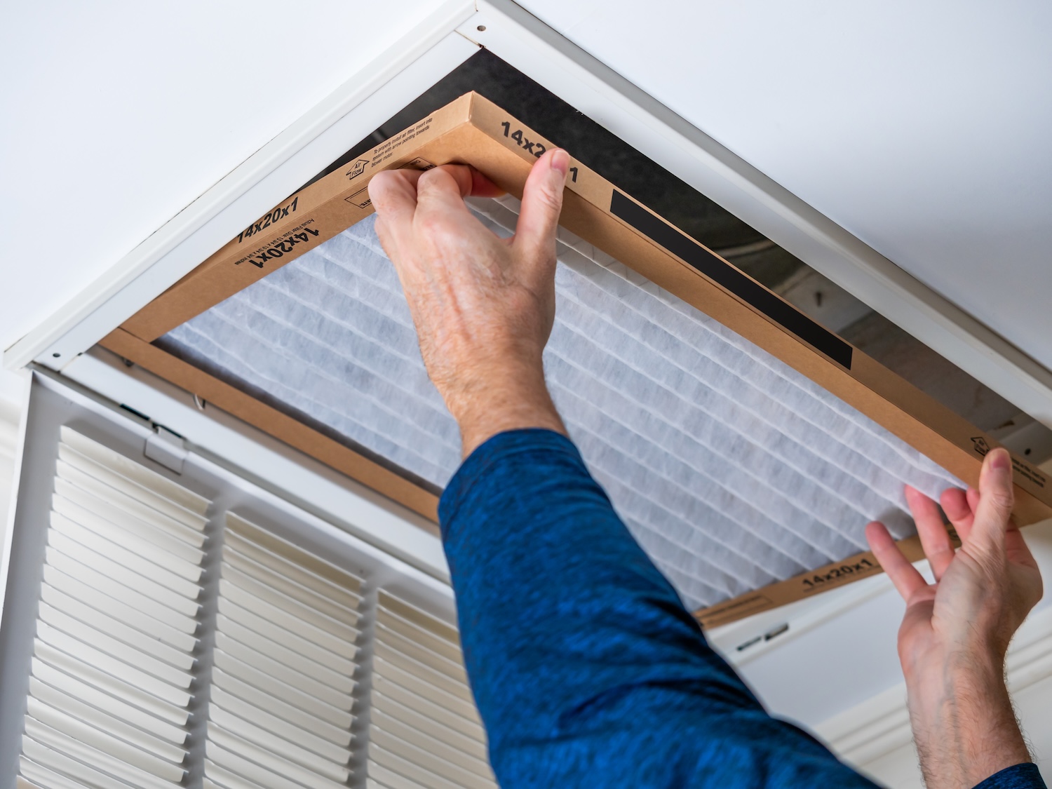 Man replacing dirty HVAC air filter in ceiling vent. Home air duct system maintenance for clean air. Man replacing dirty HVAC air filter in ceiling vent. Home air duct system maintenance for clean air.