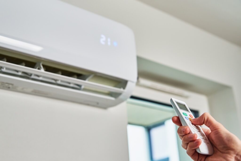 Hand adjusting temperature on air conditioner Hand adjusting temperature on air conditioner with remote control