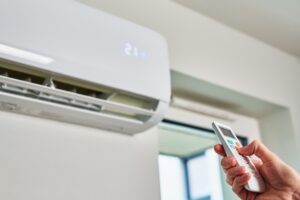 Hand adjusting temperature on air conditioner with remote control