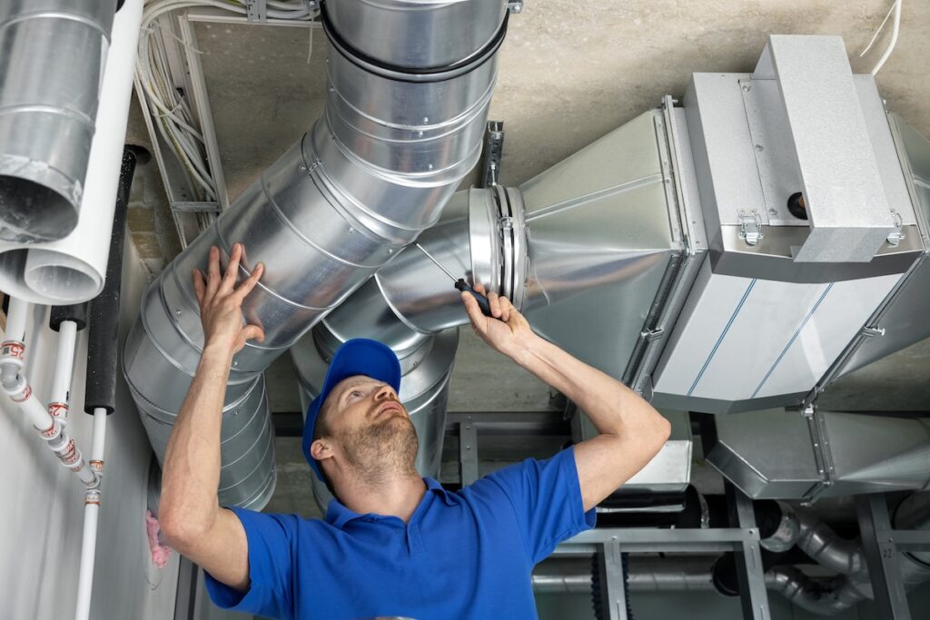 worker installing ducted pipe system for ventilation and air conditioning in house