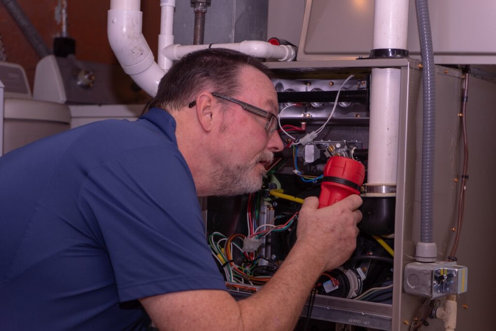 Tech Troubleshooting A Furnace Blue Shirt Troubleshooting hvac system using a flashlight to look closely